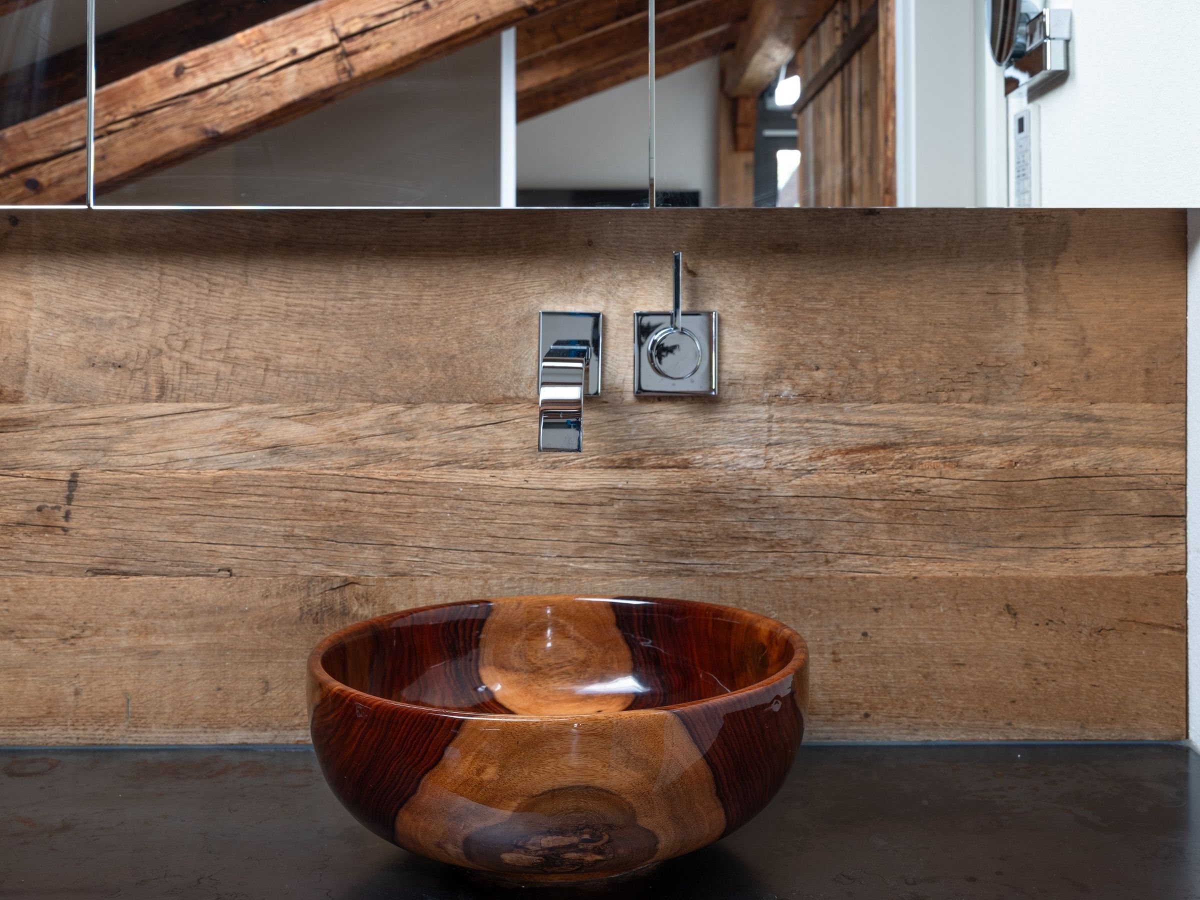Penthouse bathroom: wooden basin by John Williams in front of a reclaimed-wood wall