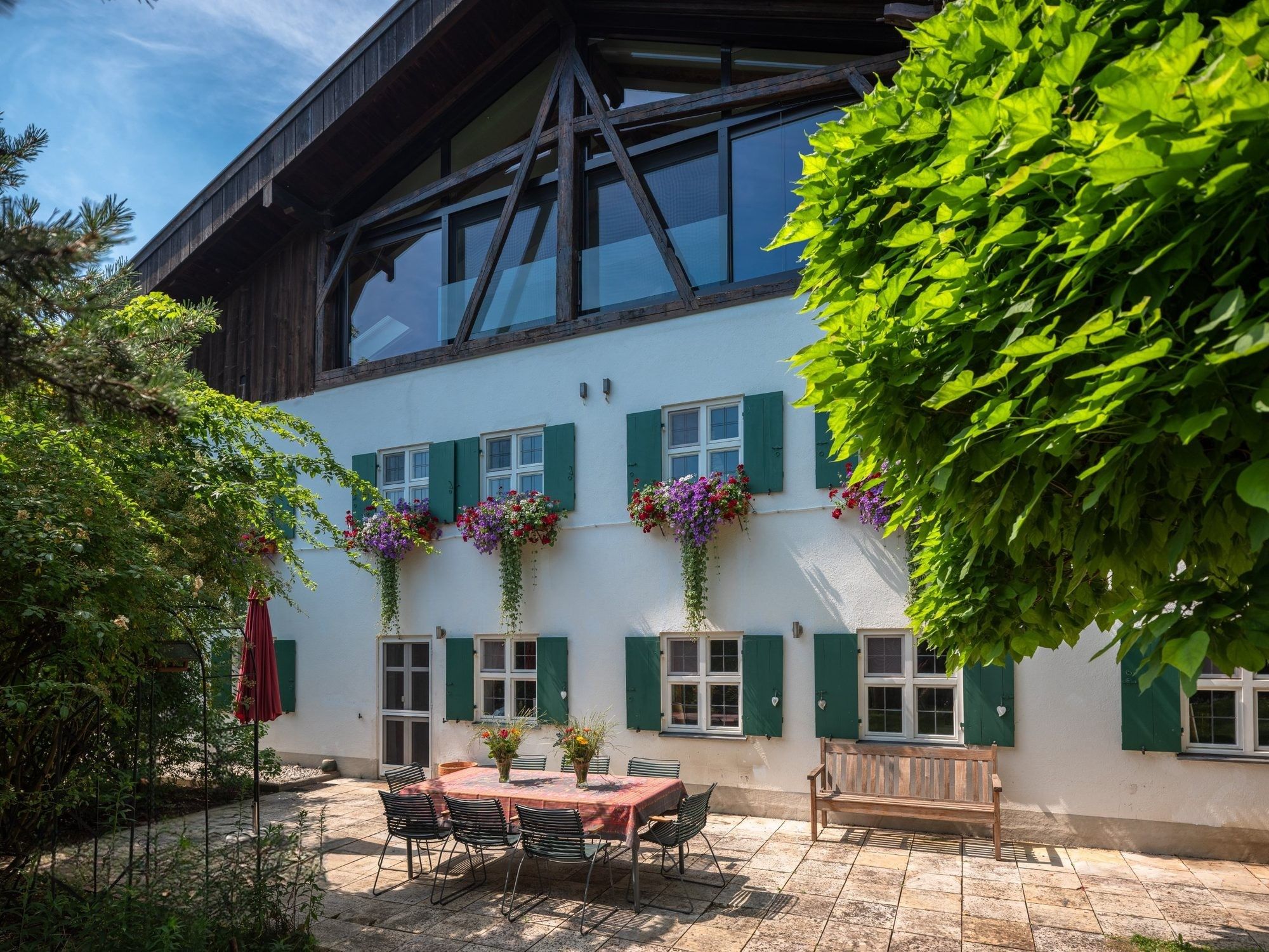 Gartenseite mit Terrasse, gedecktem Tisch und Blumenkästen
