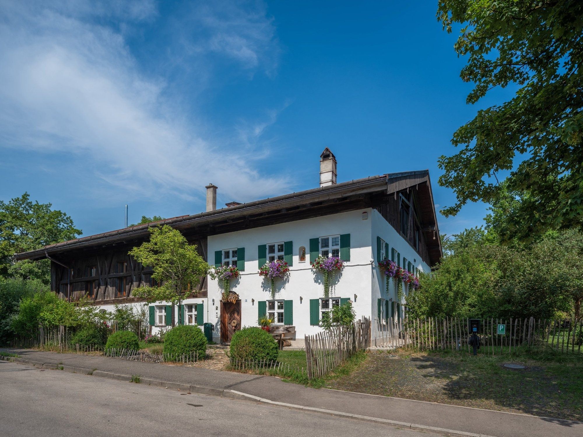 Gut Stohrerhof von der Straße: weißes Bauernhaus mit grünen Fensterläden und altem Holzstadel