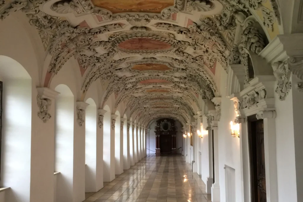 Langer Gang im Kloster Wessobrunn mit reichem Stuck an der gewölbten Decke und hellem Steinboden