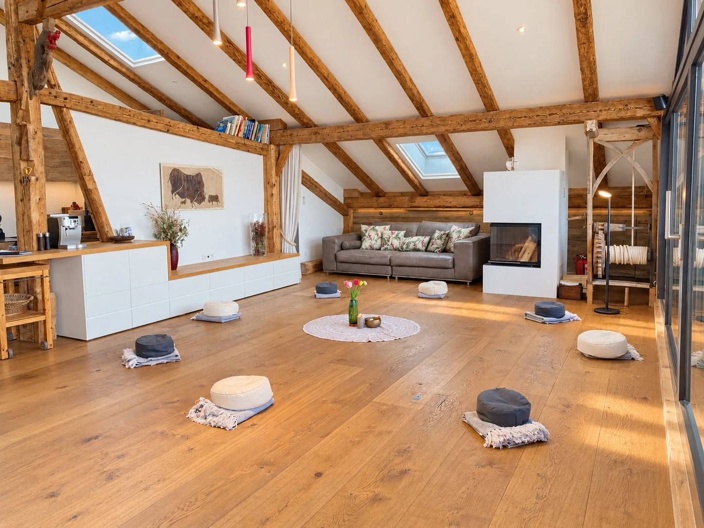 The penthouse as a private retreat space: floor cushions in a circle, fireplace and open roof timbers